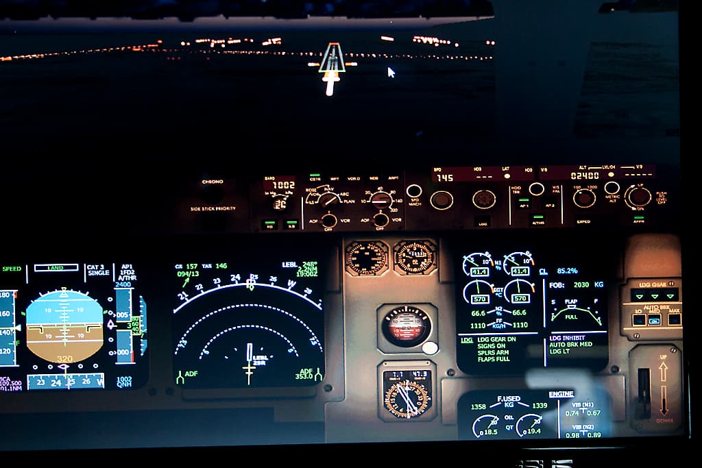 An Airbus A320 on final approach with landing gear down over the airport.