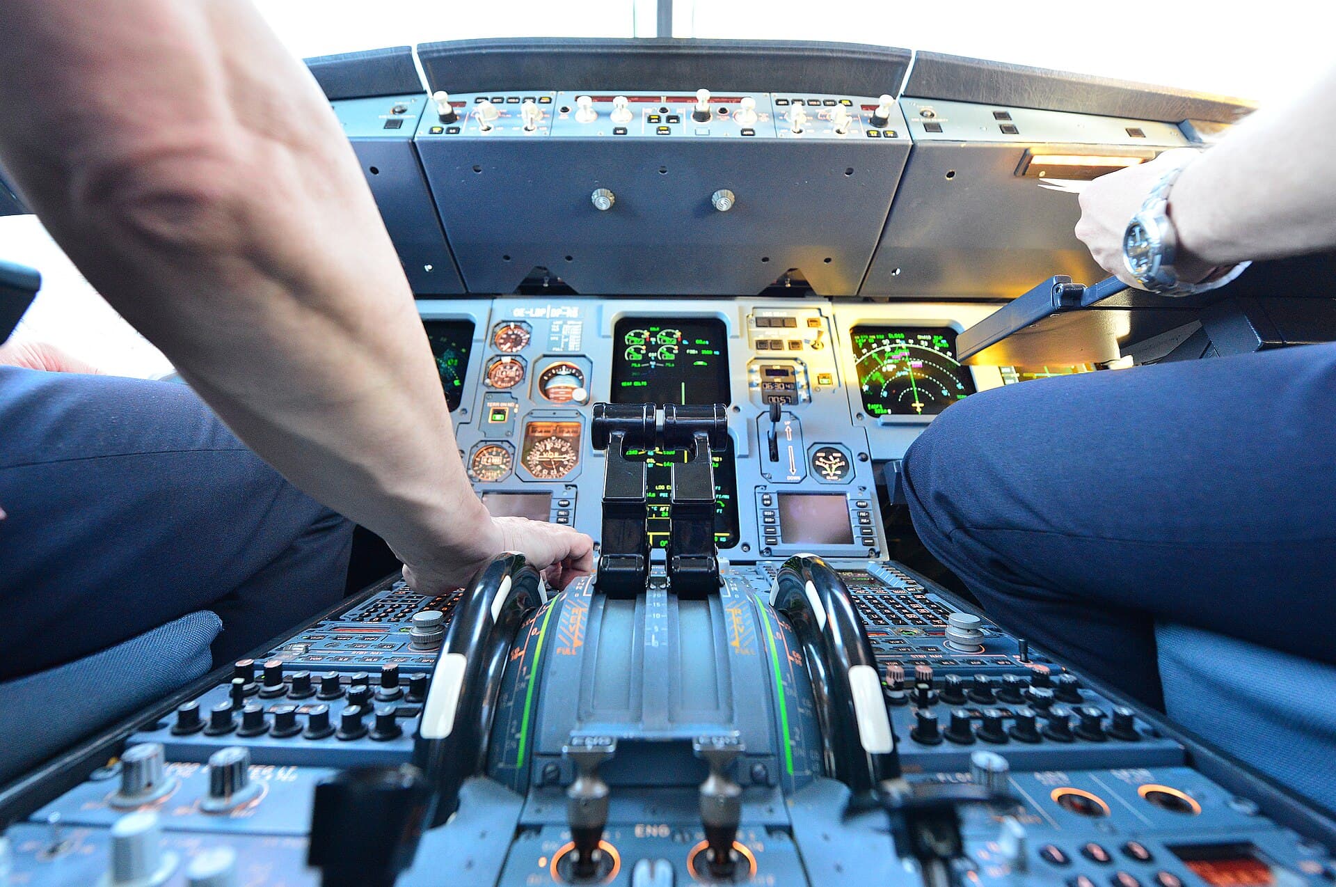 Two airline pilots working through pre-flight checks in an Airbus flight deck.