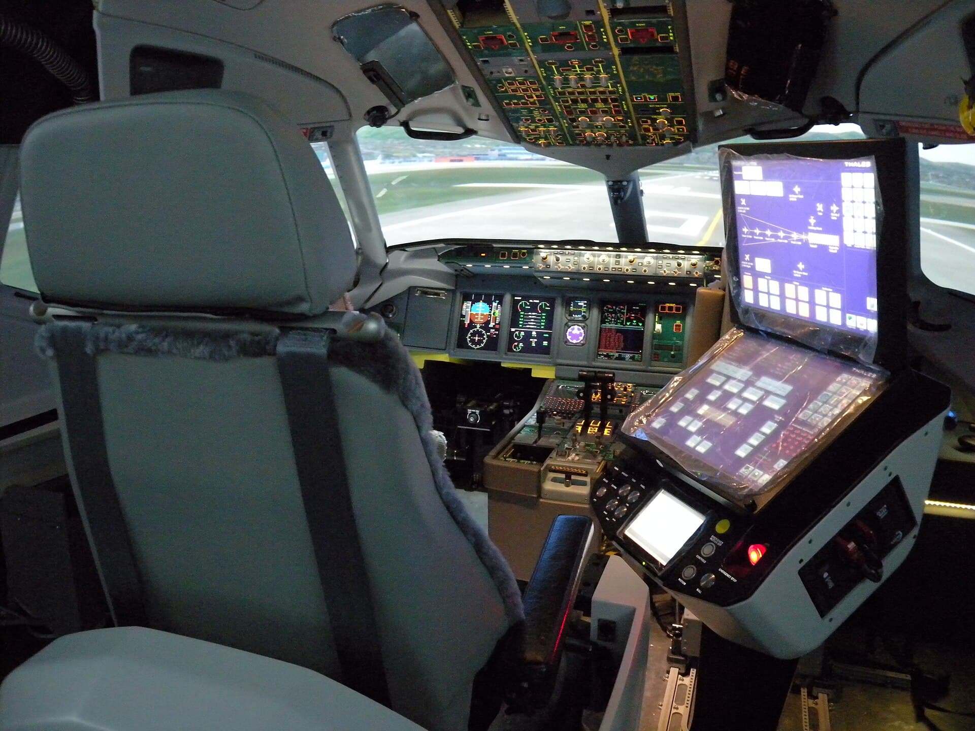 A full flight simulator cockpit used for airline pilot training, with controls and displays lit.